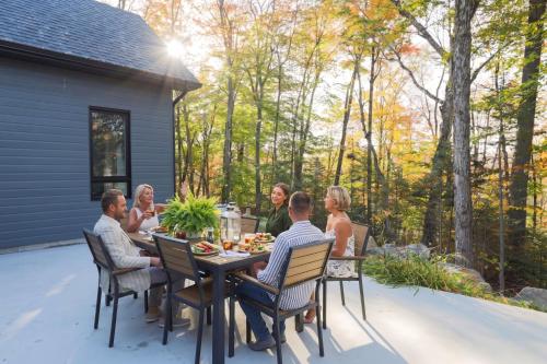 a group of people sitting around a table on a patio at Chalet Boréale with Private Spa & Billiards, Golf & Carling Lake in Brownsburg