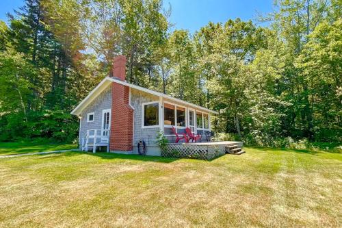 a small house with a porch on a field at Classic home overlooking the St George River with deck & great views in Saint George