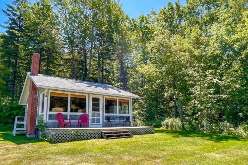 a small house with two chairs in a yard at Classic home overlooking the St George River with deck & great views in Saint George