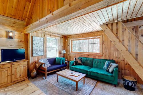 a living room with a green couch and a tv at Cozy woodsy Cabin w/ a Deck, Firepit, Gas Grill, Free WiFi, & Full Kitchen in Greenville