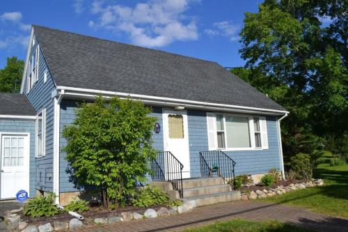 a blue house with a tree in front of it at Charming Coastal House with Cozy Living Spaces and Outdoor Firepit in Winter Harbor