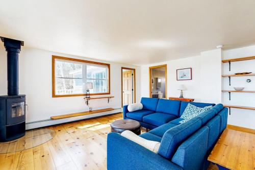 a living room with a blue couch and a fireplace at Dog-friendly river-view home with wood stove, deck, patio, dock, beach, grill in Boothbay