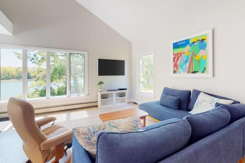 a living room with a blue couch and a tv at Water-view retreat with beach access, deck, grill, EV charger & lawn games in North Harpswell