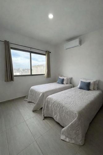 two beds in a room with a large window at Private pool house near the beach in Heroica Alvarado