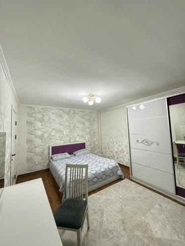 a bedroom with a bed and a chair in it at Zirek House in Bishkek