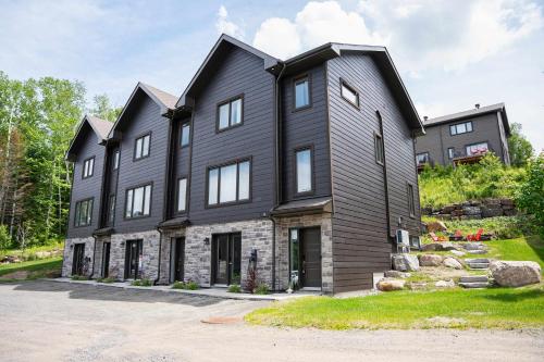 a black house with a gambrel roof at Chalet Essentiel 76 in Saint-Faustin