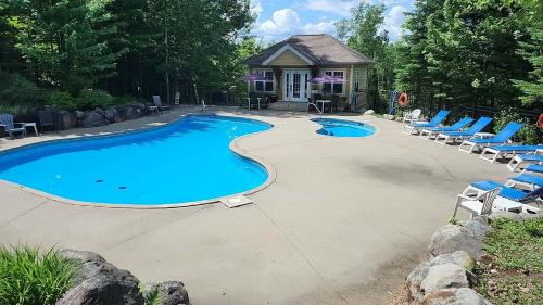 a swimming pool with lounge chairs and a house at Chalet Essentiel 76 in Saint-Faustin