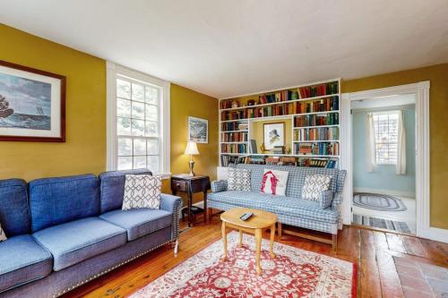 a living room with two blue couches and a book shelf at Historic riverfront home with boathouse & private dock - dogs OK in Boothbay