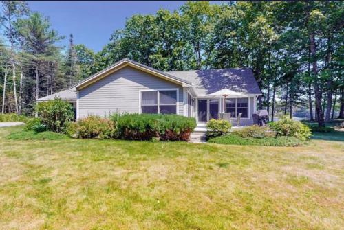 a small white house with a yard at Secluded lakefront home with patio & firepit, fast WiFi, wood stove & W/D in Ellsworth