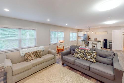 a living room with two couches and a kitchen at Waterfront home with deck, patio, grill, firepit, Ping-Pong, & WiFi in Somesville