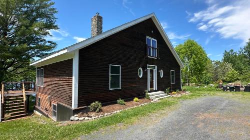 a black house with a chimney on the side of it at Lakefront home with outdoor firepit & private dock - near downtown in Greenville