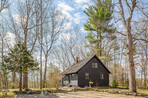 a black house in the middle of the woods at Renovated woodland home with lovely deck & firepit - minutes to Swan Lake in Swanville