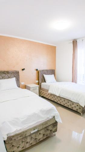two beds in a room with white sheets at Family Inn in Subotica