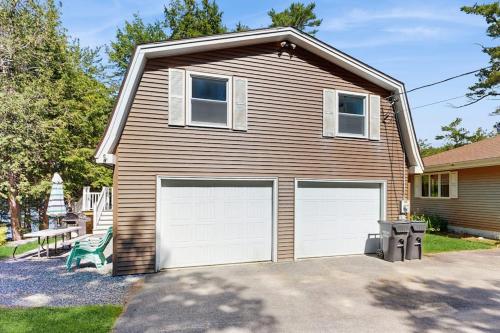 a house with two garage doors in a driveway at Secluded waterfront home with private dock, outdoor dining, firepit, WiFi & W/D in Orland