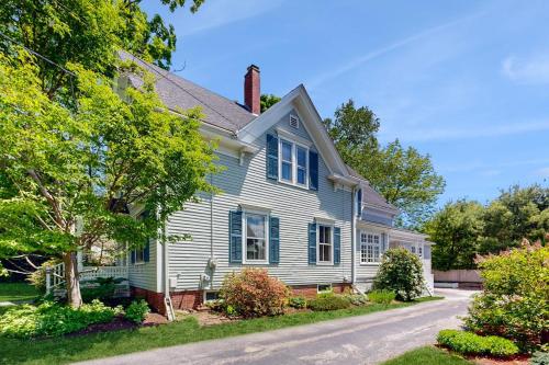 a white house with blue shutters on a street at Parker House: Historic home - walk downtown, dog-friendly & washer/dryer in Camden