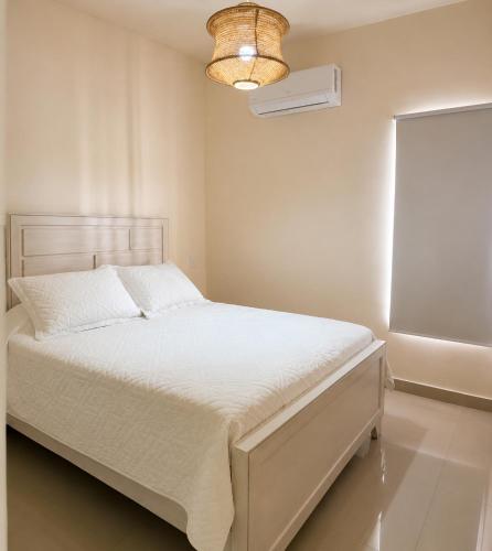 a bedroom with a white bed and a light fixture at Eco Avalon Paradise Villa in Punta Cana