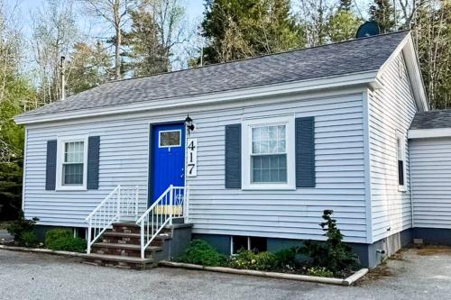 a white house with a blue door at Open layout Maine cottage with washer/dryer & grill - dog-friendly in Gouldsboro