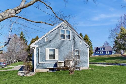a blue house in a yard with a house at Charming Coastal House with Cozy Living Spaces and Outdoor Firepit in Winter Harbor