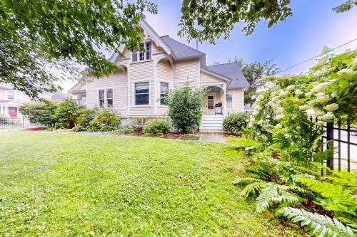 a white house with a fence and a yard at Dog-friendly historical home with recent updates, porch & prime in-town location in Rockland
