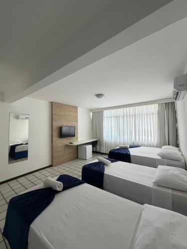 a hotel room with three beds and a desk at Praia Hotel Enseada in Maceió