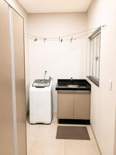 a white bathroom with a sink and a window at Vêneto Flat Residence (AP-02) in Primavera do Leste