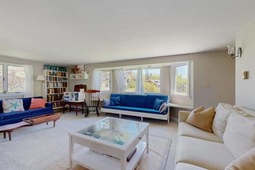 a living room with blue couches and a table at Ocean Point Colony Home w/ Sunroom & Sweeping Ocean Views, Dog-friendly in East Boothbay