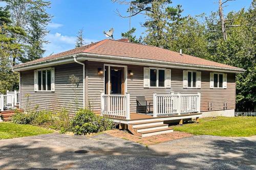 a small wooden house with a porch and a door at Secluded waterfront home with private dock, outdoor dining, firepit, WiFi & W/D in Orland