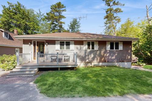 a house with a large porch with a yard at Secluded waterfront home with private dock, outdoor dining, firepit, WiFi & W/D in Orland