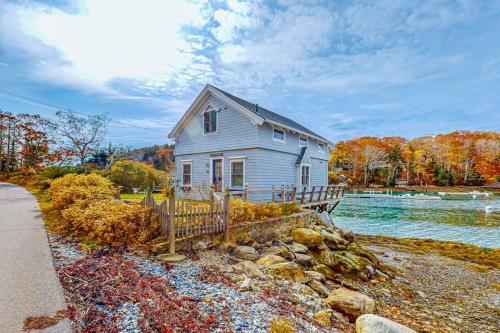 a house sitting on the side of a river at Enchanting Oceanfront Cottage with Breathtaking Views and Modern Comforts in East Boothbay