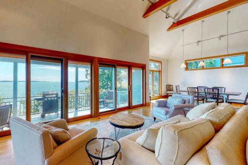 a living room with a couch and chairs and a table at Delightful oceanfront home with amazing views, wrap-around deck & two fireplaces in Wiscasset