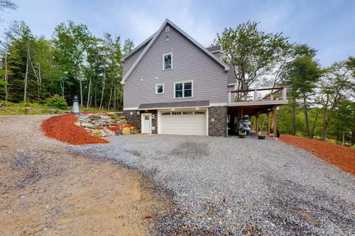 a gray house with a garage on a gravel driveway at Luxurious waterfront home with deck, firepit, hot tub, fireplace, & pool table in Boothbay