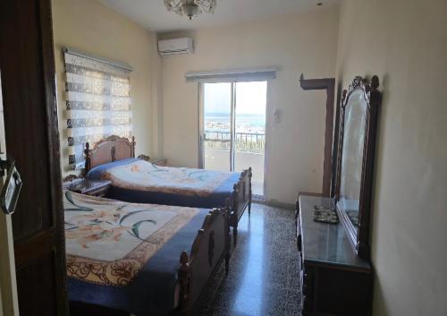 a bedroom with two beds and a mirror and a window at Super sea promenade apartment in El Mîna