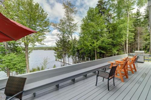 a row of chairs and tables on a deck next to the water at Lakefront Chalet-Style Home with Large Deck, a Dock & Beautiful Lake Views in Greenville