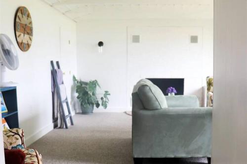 a white living room with a chair and a clock at Ocean-view cottage near beach with deck, grill, & full kitchen in Bristol