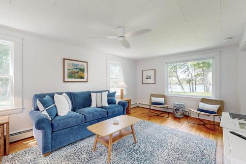 a living room with a blue couch and a table at Tranquil Seaside Cottage with Spectacular Views, Wifi & Washer/Dryer in Boothbay
