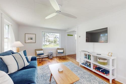 a living room with a blue couch and a tv at Tranquil Seaside Cottage with Spectacular Views, Wifi & Washer/Dryer in Boothbay