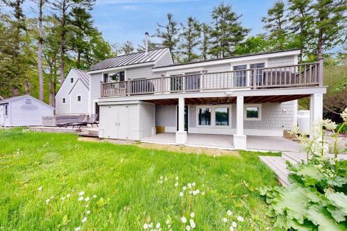 ein großes weißes Haus mit einer großen Terrasse in der Unterkunft Stunning riverfront home, hot tub, BBQ, and washer & dryer in Edgecomb