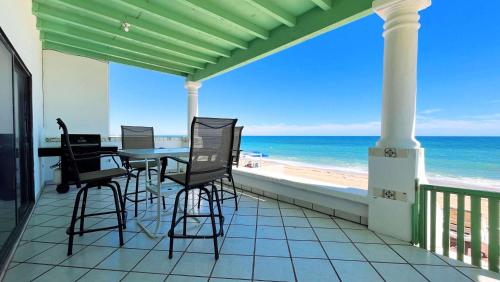 a balcony with a table and chairs and the beach at Comfortable Beachfront Condo Las Olas II 1 in Puerto Peñasco