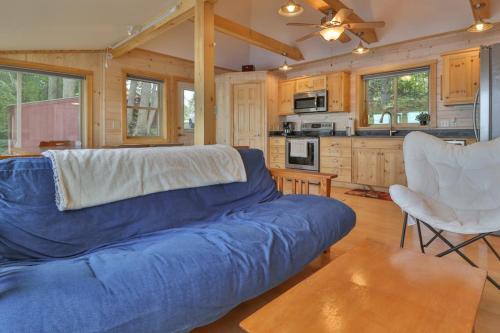 a living room with a blue couch and a kitchen at Luxe Bayfront Cabin w/ Stunning Views & Shared Dock- Ideal for Hunting & Fishing in Bowdoinham