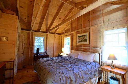 a bedroom with a bed in a wooden room at Berry Cottage, private dock, overlooking a sandy b in South Thomaston