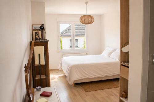 a bedroom with a white bed and a window at Le Forest - Saint-Cyr-l'École in Saint-Cyr-lʼÉcole