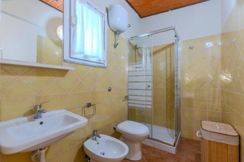 a bathroom with a sink and a toilet and a shower at L'Agrumeto domos in Teulada