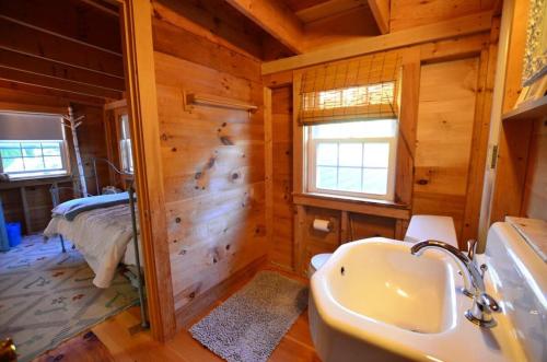 a bathroom with a sink and a bed in a room at Berry Cottage, private dock, overlooking a sandy b in South Thomaston