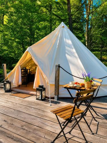 a tent with a table and a chair on a deck at Glamping-Dimbo in Krynica Zdrój