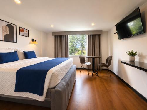 a hotel room with a bed and a table and chairs at Hotel Embajada 44 in Bogotá