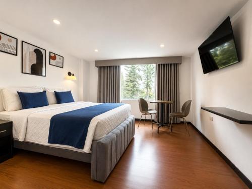 a hotel room with a bed and a table and chairs at Hotel Embajada 44 in Bogotá