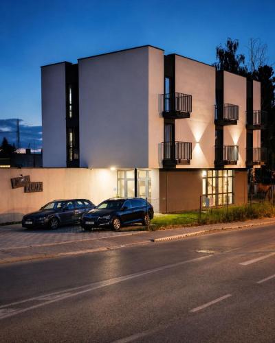 two cars parked in a parking lot in front of a building at Penzión Alma in Poprad