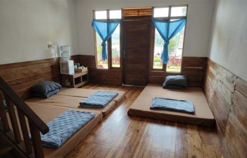 a room with three beds on the floor and windows at Home Stay TB2 in Palayangan