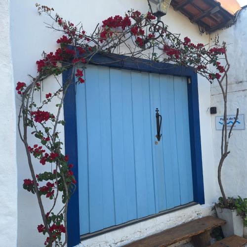 a blue garage door with red flowers in front of it at Pouso do Rio in Pirenópolis