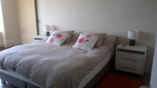 1 cama blanca con 2 almohadas y una mesita de noche en Apartamentos Arenamaris, en Algarrobo
